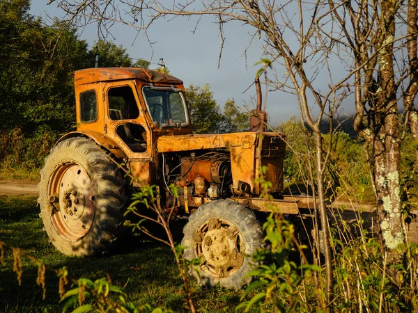 An old rusty orange tractor with dents and scratches