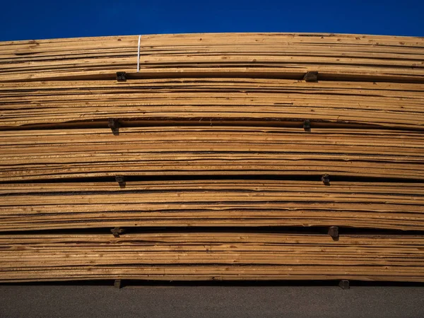 Heap of wooden boards in sawmill or in a warehouse. Storage of a large number of the sawn boards for sale. Production of wooden construction materials