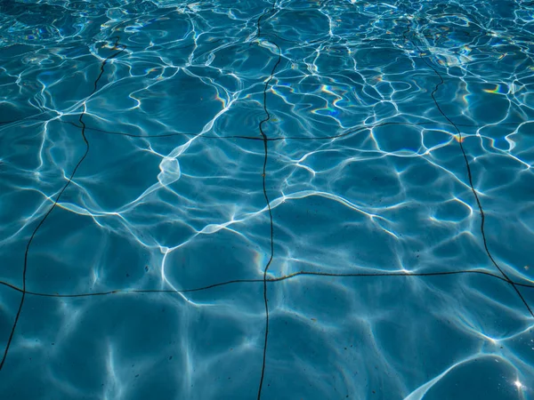 Dirty pool filled with water. The sun creates glare on the surface of the water