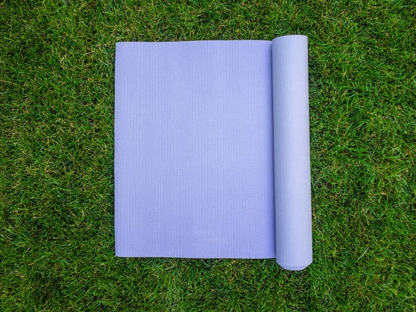 Purple yoga Mat on the grass. Mat for yoga, Pilates or fitness. Mat without people