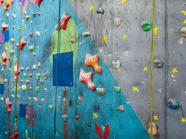 Training wall climbing wall. Hooks and ropes for training climbers. Rock climbers training center