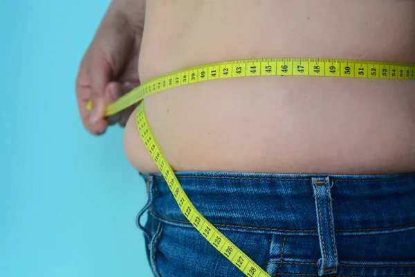 Woman measures a fat belly. Healthy lifestyles concept. Background to obesity