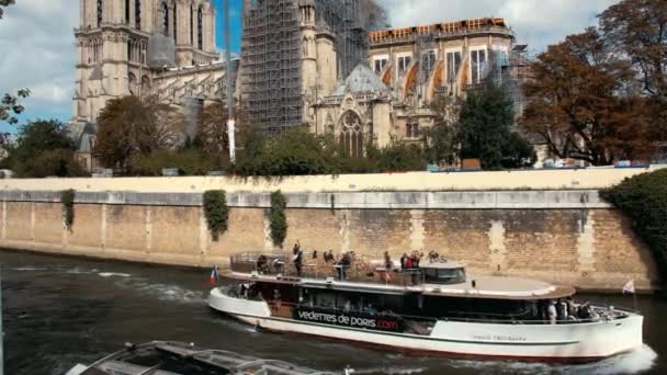 Париж, Франция - сентябрь 2019 года: реставрация собора Парижской Богоматери после пожара. Туристический корабль плывет вдоль реки Сены. Панорамный снимок . — стоковое видео