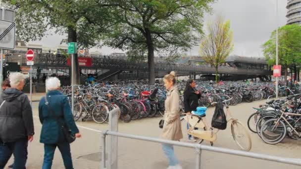 Amsterdam, Niederlande - Oktober 2019: Anwohner eilen vor dem Hintergrund eines mehrreihigen großen Fahrradabstellplatzes in der Innenstadt ihrem Geschäft nach. Umweltschutzkonzept — Stockvideo