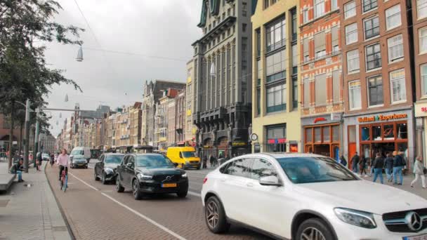 AMSTERDAM, Olanda - Ottobre 2019: varietà di auto e ciclisti che percorrono le strade della città. Amsterdam case storiche sullo sfondo — Video Stock