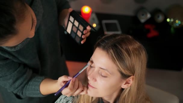 Makeup Artist tillämpar ögonskugga. Vackert kvinnoansikte. Perfekt makeup. Ögonskuggspalett — Stockvideo