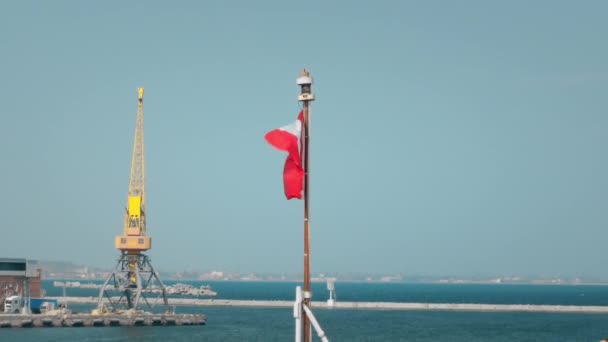 Drapeau du Canada agitant le vent. Accroché au mât d'un navire de l'OTAN amarré dans un port. Dans le contexte d'une grue pour le transbordement de marchandises 