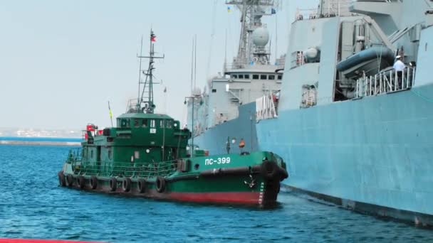 Green tugboat is working with a NATO warship — Stock Video