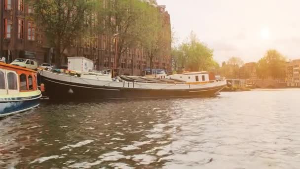荷兰阿姆斯特丹- 2019年9月：首都运河中的游艇。 市中心的房屋立面。 日落了 光线照射在相机上 — 图库视频影像