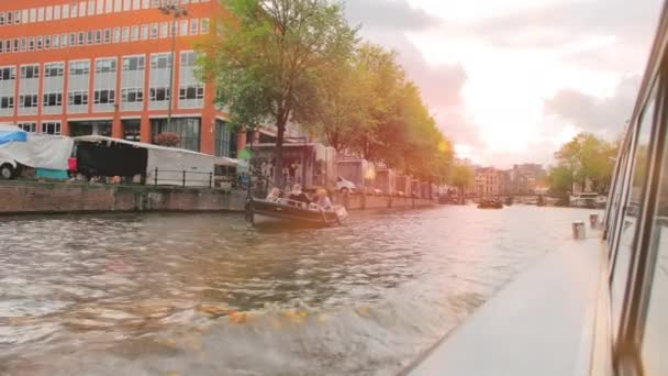 Amsterdam, Nizozemsko - září 2019: Lodě na kanálu v hlavním městě. Z úhlu pohledu. Slunce svítí v rámu — Stock video