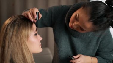 Kadın stilist makyaj sanatçısı kız için kaş şekli formu yapma, yakın çekim yüz. Genç kadın model güzellik salonu. Fırça kullanarak boya uygulama. Glamour şık moda endüstrisi. Visagiste çalışma