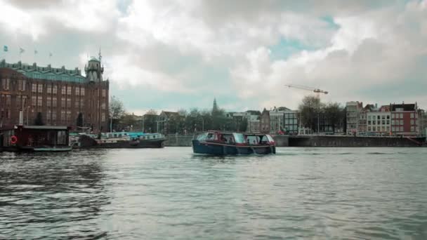 Amszterdam, Hollandia - 2019. szeptember: Csónak az Amstel folyón. A háttérben a főváros hagyományos házai állnak. — Stock videók