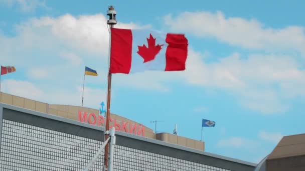 Kanadai zászló a hajó zászlórúdján, a tengeri kikötő termináljának hátterében — Stock videók