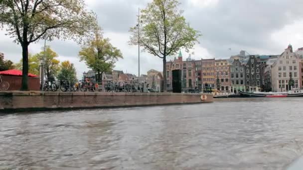 Amsterdam, Niederlande - September 2019: Fahrräder, die auf der Promenade im Zentrum der Hauptstadt abgestellt sind. Im Hintergrund sind typisch holländische Häuser zu sehen. — Stockvideo