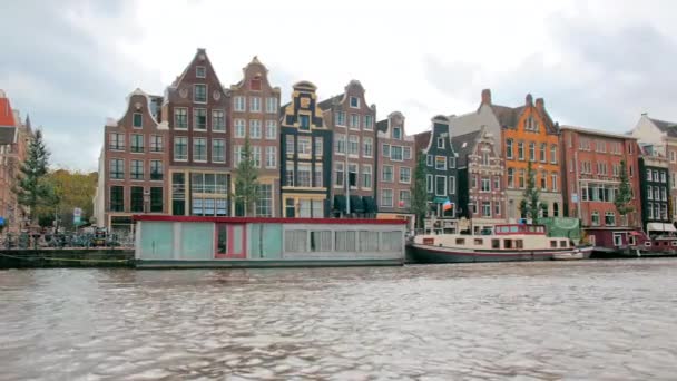 Amsterdam, Netherlands - September 2019: Landmark dancing houses. View from the canal. Houseboats are moored near the shore — Stock Video