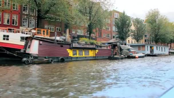 Amsterdam, Nederländerna - september 2019: Bizarra husbåtar förtöjda på gatorna. Fasader av hus i centrum. Utsikt från kanalen — Stockvideo