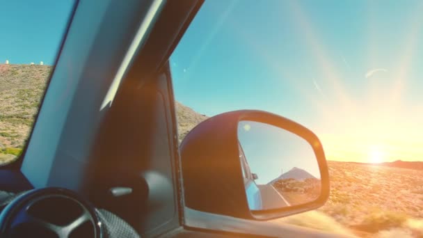 Gipfel eines Vulkanberges, der sich während der Fahrt im Rückspiegel eines Autos spiegelt. die Strahlen des Sonnenuntergangs in die Kamera. das Konzept des Reisens, die Beförderung zum Ziel, der Erfolg