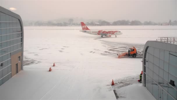 Lviv, Ukraina - Januari 2019: orange ernest passagerarflygplan anlände, rör sig längs plattformen för flygfältet. Dåligt väder. tung snöstorm och stark vind. Snöplogar. — Stockvideo