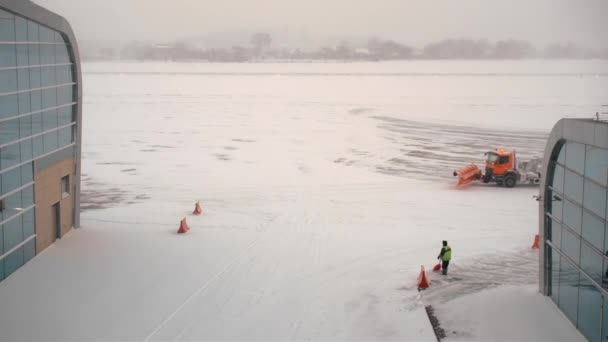 Orange snöplogar rengör banan och förklädet på flygfältet. Snöfall och snöstorm. Koncept för fördröjning av väderavvikelser — Stockvideo