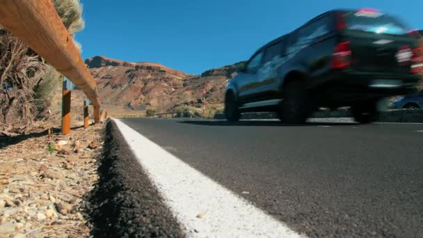 Non riconosciuto nero off-road traversata in auto lungo una strada asfaltata di montagna nel deserto. Luminose indicazioni stradali. Sullo sfondo di cime vulcaniche. Il concetto di superficie stradale perfetta — Video Stock