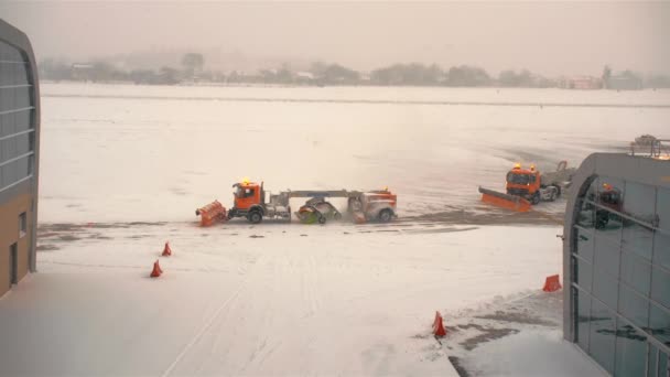 Оранжевые снегоочистители очищают взлетно-посадочную полосу и перрон аэродрома. Снег и сильный снегопад. Концепция задержки погодных аномалий — стоковое видео