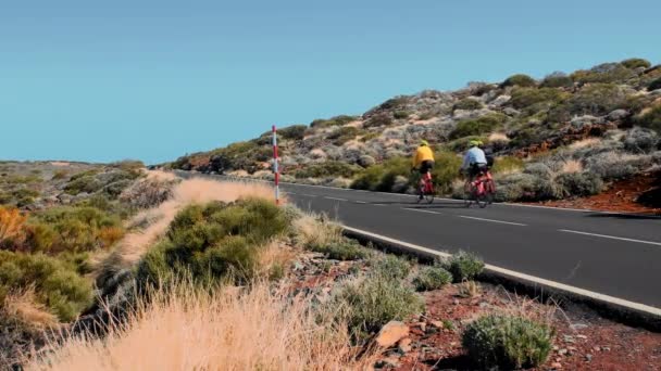 Grupo de atletas no reconocidos que suben en bicicleta por la montaña. Paisaje del desierto de terreno alpino. Nuevo camino de asfalto. Concepto de crecimiento empresarial y movimiento ascendente — Vídeo de stock