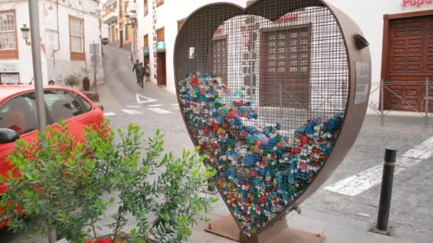 Insulele Canare, Spania - ianuarie 2019: conceptul de colectare a deșeurilor din plastic și a gunoiului pe străzi. Cușcă de fier în formă de inimă pentru colectarea capacelor și sticlelor pentru animale de companie. Conceptul de poluare — Videoclip de stoc