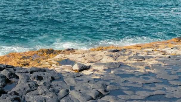 Onde turchesi dell'oceano battono contro le pietre gialle della riva. Massiccia schiuma bianca e forma spray. vicino, sole di mezzogiorno — Video Stock