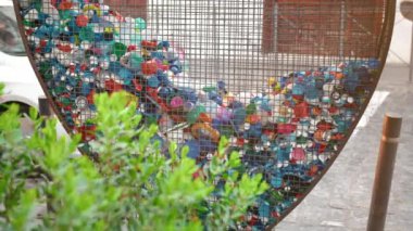 Şehirlerde plastik atık ve çöp toplama kavramı. Yeşil bitki çalısı ve hayvan örtüsü ve şişe toplamak için kalp şeklinde demir kafes. Doğa koruma kavramı, çevre kirliliği