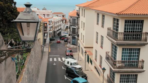 Στενός ευρωπαϊκός δρόμος με αυτοκίνητα που τρέχουν κάτω από την ακτή της θάλασσας. Σε πρώτο πλάνο είναι μια λάμπα δρόμου. Μπορεί να χρησιμοποιηθεί για να απεικονίσει την ισπανική, ισπανική. — Αρχείο Βίντεο