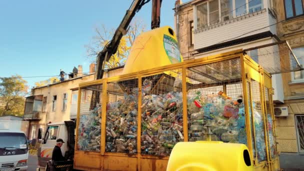 Odessa, Ukraina - November, 2019: operatör av en gul plast sopbil lossar skräp och plastflaskor från en container. Begreppet separat insamling av sopor och plast — Stockvideo