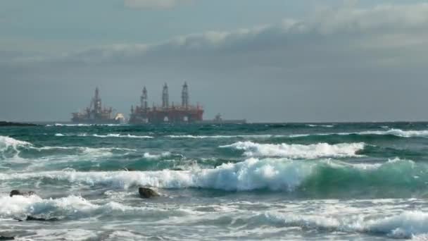 Buque cisterna cerca de plataformas petrolíferas en el océano frente a la costa. Mar tormentoso, olas y espuma. Concepto de extracción de petróleo de la plataforma oceánica y medio ambiente contaminante — Vídeos de Stock