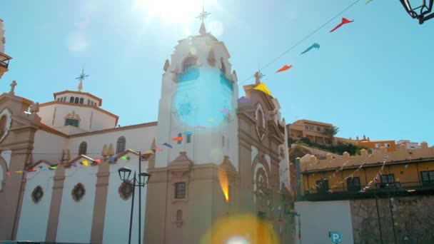 Catedral Católica Cristiana en la ciudad española. Los rayos del sol brillan en el marco, la calle está decorada con banderas festivas. El concepto de religión ligera — Vídeo de stock