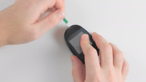 Oigenkänd man förbereder en glukosmätare för att mäta blodglukos, sockernivåer, för mätningar. Laddar en enda bandprovning i en mätanordning. Förebyggande av diabetes — Stockvideo