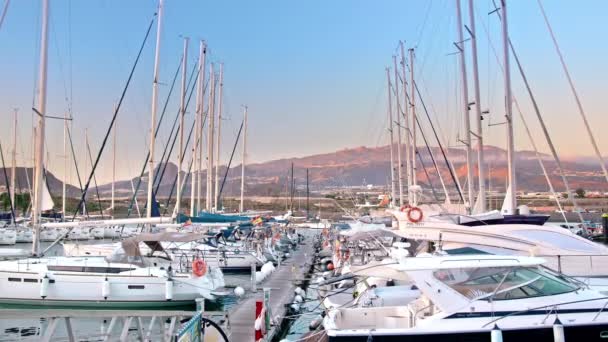 Tenerife, Ilhas Canárias, Espanha - Janeiro de 2019: Marina no oceano. Iates de luxo atracados na baía. Pôr do sol ou amanhecer, os raios de sóis iluminam lindamente os barcos. Las Galletas, Tenerife, Ilhas Canárias — Vídeo de Stock