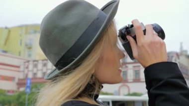 Kafkasyalı genç bir kadın, şapkalı bir hippi eski bir film kamerasıyla fotoğraf çekiyor. İşteki baskı sürümü için gazeteci blogcusu kavramı