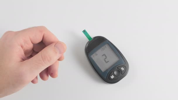 血糖値を個人用血糖値計で測定します。医療機器は標準を示しています。フレーム内の手が親指を上に表示します。糖尿病の概念予防 — ストック動画