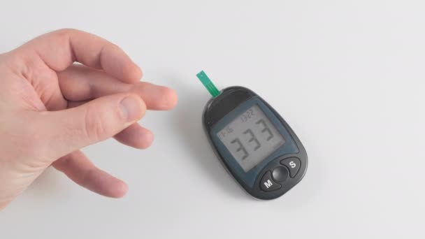 Een onbekende man meet de bloedsuikerspiegel. Doorboort de huid van de vinger met een pen en brengt een druppel bloed aan op een weggegooide teststrip. Conceptpreventie van diabetes — Stockvideo