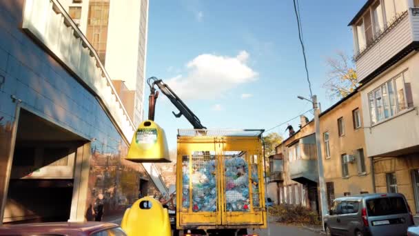 Odessa, Ukraine - November, 2019: Manipulator arm of a yellow plastic garbage truck picks up a trash bin and plastic bottles. The concept environmental protection, waste recycling — Stockvideo