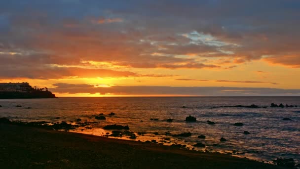 Colorful bright dramatic sunset, dawn on the ocean. The sun rises from beyond the horizon, illuminates the sea with rays. The multi-coloured sky is orange, yellow, pink and blue — ストック動画