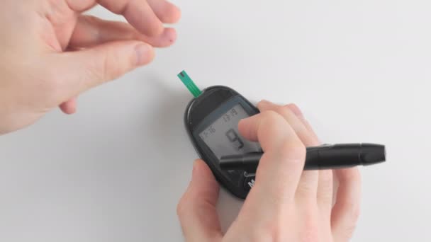 An unrecognized person measures blood glucose with a glucometer. Squeezes a drop of blood and puts a single strip test. Measuring 6.2 mmol. Concept prevention of diabetes. — Stock Video