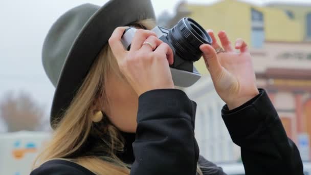 Egy fiatal kaukázusi nő, egy kalapos hipszter lefényképez egy régi filmkamerát. Concept újságíró blogger nyomtatott kiadás a munkában. — Stock videók
