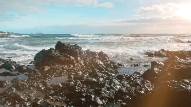 Uma pedra de lava no oceano com o nascer do sol. Torres para a produção de equipamento de petróleo no fundo. Conceito de protecção do ambiente e poluição dos oceanos — Vídeo de Stock