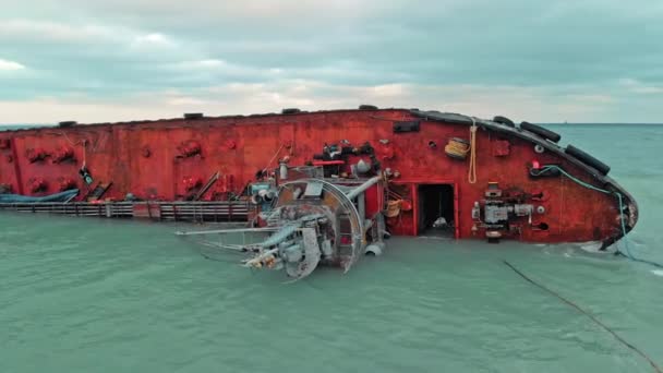 Nave da carico si trova sul suo lato, vicino alla riva di una spiaggia sabbiosa con una barriera alla zona di inquinamento dopo il naufragio della nave. drone aerea colpo — Video Stock