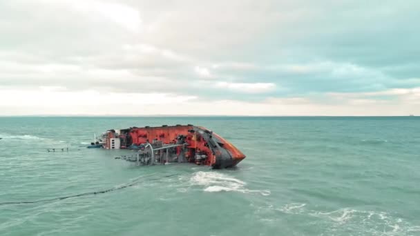 Kargo gemisi bir tanker karaya oturdu ve bulutlu havada dalgalarla denize yuvarlandı, insan yapımı bir felaket, gemiden yayılan emisyonlarla deniz ekosisteminin kirlenmesi. Hava aracı görüntüsü — Stok video