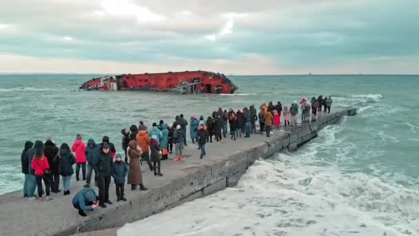 Odessa, Ukraine - November 2019: En miljøkatastrofe. Mange mennesker på stranden tager billeder af et tankskib, der gik på grund og væltede om bord under en voldsom storm. Luftdrone skud – Stock-video