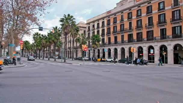 Ismeretlen autók, taxik, kerékpárosok és helyiek Barcelona központjában, egy keresztút forgalmas forgalom. Körút pálmafákkal a háttérben. — Stock videók