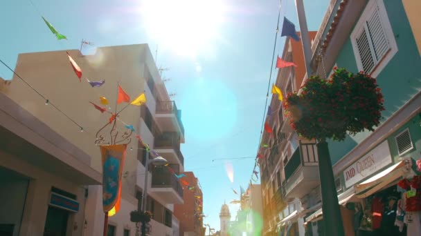 Tenerife, Canarische Eilanden, Spanje - januari 2019: Een feestelijk versierd met kleurrijke vlaggen, straat in de Spaanse stad. Zonnestralen en een positieve atmosfeer — Stockvideo