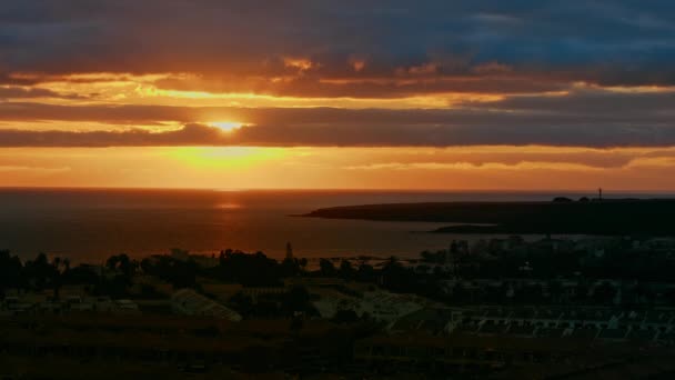 Pôr-do-sol laranja sobre o mar. Raios coloridos do sol e do brilho no momento do pôr do sol ou do amanhecer sobre a cidade perto do oceano, grande disco de sol e nuvens dramáticas — Vídeo de Stock