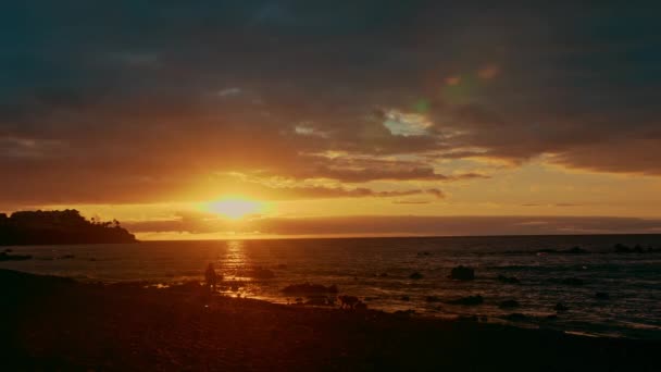 Красочный яркий драматический закат, рассвет в океане. Солнце встает из-за горизонта, освещает море лучами. Многоцветное небо оранжевое, желтое, розовое и голубое — стоковое видео